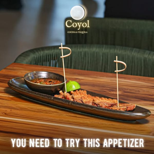 Crispy appetizer pieces with lime and dipping sauce on a black platter at Coyol Cocina & Tequila.